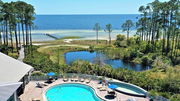 A resort with a large pool, lounge chairs, and a view of the ocean. - Endless Summer: Double porches w/ Ocean views, resort pool! 1-min walk to beach! (Saint Teresa)