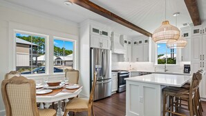A modern kitchen with white cabinetry, stainless steel appliances, and a large island. - Endless Summer: Double porches w/ Ocean views, resort pool! 1-min walk to beach! (Saint Teresa)