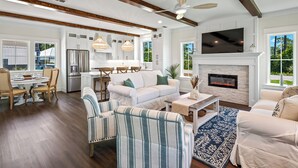 A spacious living room with a fireplace, a dining area, and a kitchen. - Endless Summer: Double porches w/ Ocean views, resort pool! 1-min walk to beach! (Saint Teresa)