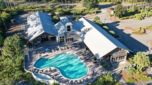 An aerial view of a resort with a large swimming pool, lounge areas, and a building with a sloped roof. - Endless Summer: Double porches w/ Ocean views, resort pool! 1-min walk to beach! (Saint Teresa)