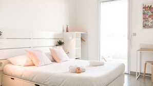 A modern hotel room with a large bed, a wardrobe, a desk, and a view of the outside. - Bail mobilité - Appart 2 ch parking et terrasse (Marseille)