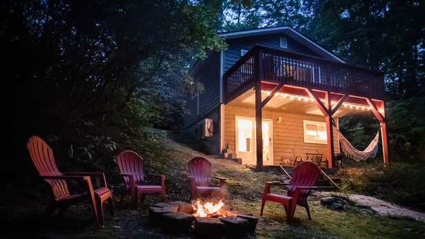 Een chalet met terras, vuurkorf en rode Adirondack stoelen.