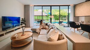 A modern living room with a TV, sofa, and dining area. - Villa De Time The Luxury Private Pool Villa (Pattaya)