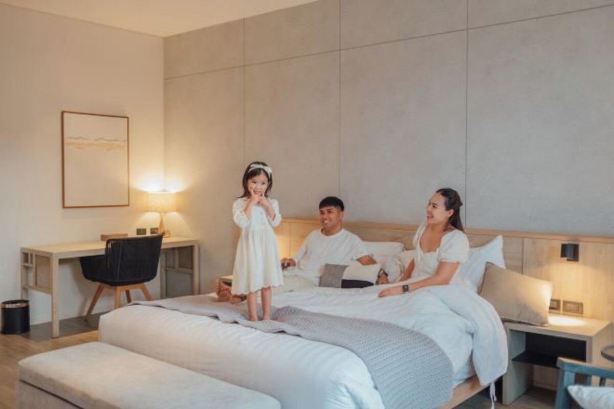 Une chambre d’hôtel moderne avec un grand lit, des tables de chevet, un bureau et une chaise.