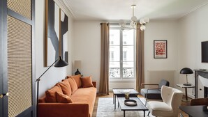 A modern living room with a sofa, armchairs, a coffee table, and a TV.
