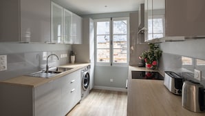 Eine moderne Küche mit integriertem Geschirrspüler, Edelstahlgeräten und einem großen Fenster für natürliches Licht.