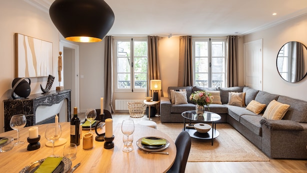 Ein modernes Wohnzimmer mit Essbereich, einer Sofagarnitur, einem runden Couchtisch und einer großen schwarzen Pendelleuchte.