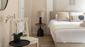 Ein Schlafzimmer mit Bett, Stuhl, einem kleinen Tisch mit Pflanze, Lampe und Wand mit einem einzigartigen Design.