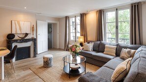 Ein modernes Wohnzimmer mit Kamin, einer Couch, einem Glastisch und einem Essbereich.