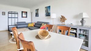 A modern living room with a dining table, chairs, a sofa, and a cabinet with dishes.