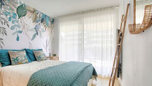 A bedroom with a bed, a ladder, and a wall with a leaf pattern.