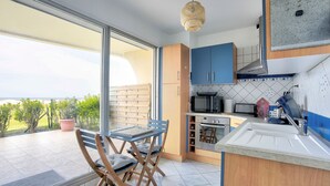A modern kitchen with a large window, a dining area with a table and chairs, and a view of the outdoors.