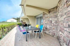 Een terras buiten met een stenen muur, een tafel voor vier personen en kleurrijke stoelen.