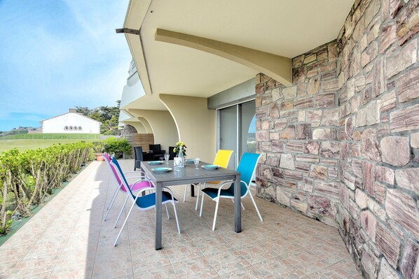 Eine Terrasse im Freien mit einer Steinmauer, einem Tisch für vier Personen und bunten Stühlen.