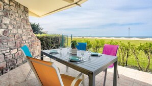 A patio with a table set for dining, stone wall, and a view of the sea.