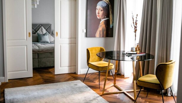 Ein modernes Zimmer mit einem Bett, einem runden Tisch, zwei Stühlen und einem Bild an der Wand.
