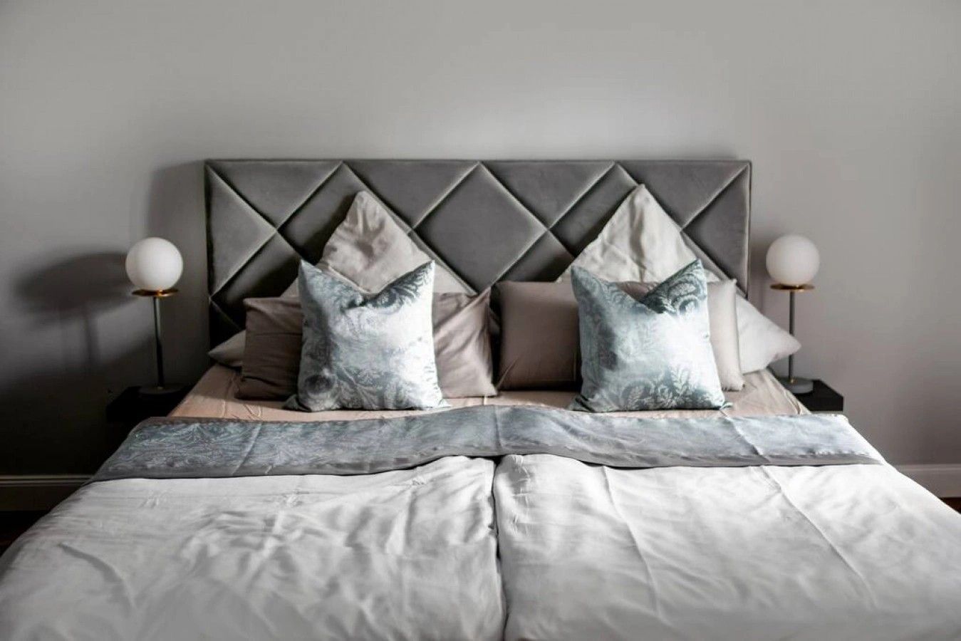Una cama con cabecera, almohadas y una lámpara de noche.