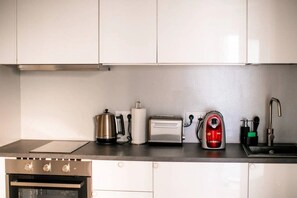 A kitchen with stainless steel appliances, a toaster, a kettle, and a sink.