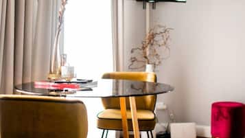 Una sala de estar moderna con una mesa redonda de vidrio, una butaca amarilla, un reposapiés rojo y un televisor de pantalla plana montado en la pared.