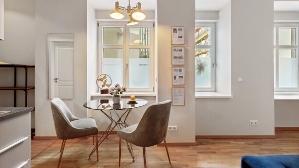 Ett modernt kök med en matplats, med ett runt bord och två stolar, en hänglampa och ett fönster med utsikt över omgivningen.