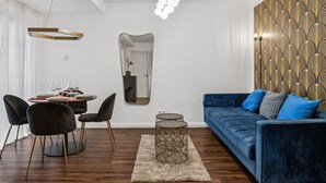 A modern living room with a blue sofa, black chairs, a dining table set for two, a round coffee table, and a large mirror. - Arbio I New renovated Apart Schöneberg S-Bahn (Berlin)