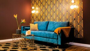 A room with a blue sofa, a patterned wallpaper, and a decorative light fixture. - Arbio I New renovated Apart Schöneberg S-Bahn (Berlin)