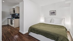 A bedroom with a bed, a green blanket, white pillows, and a framed picture on the wall. - Arbio I New renovated Apart Schöneberg S-Bahn (Berlin)