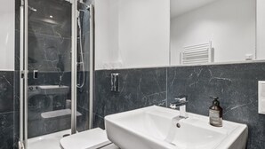 A modern bathroom with a glass-enclosed shower, a white toilet, and a large sink with a soap dispenser. - Arbio I New renovated Apart Schöneberg S-Bahn (Berlin)