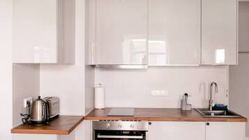 Een koelkast, een oven, een kookplaat, kookgerei, borden en bestek