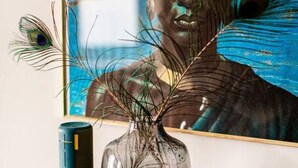 A framed artwork on a wall, a vase with decorative branches, a candle, and a small bottle on a table. - Arbio I Cozy Apart in Charlottenburg (Berlin)