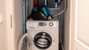A compact laundry room with a front-loading washing machine and a stacked washer and dryer unit. - Arbio I Cozy Apart in Charlottenburg (Berlin)