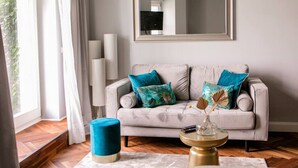 A living room with a sofa, two decorative vases, a round coffee table, and a large mirror on the wall. - Arbio I Cozy Apart in Charlottenburg (Berlin)
