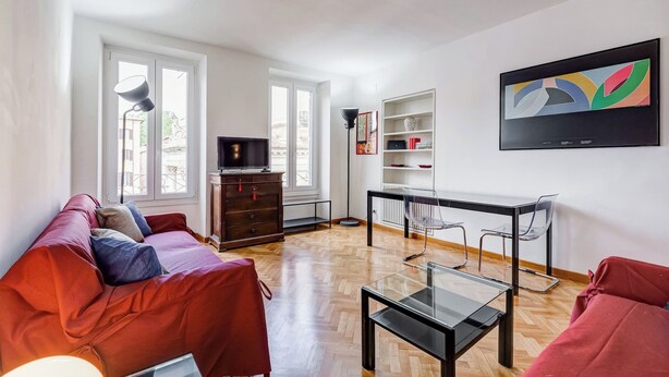Ein modernes Wohnzimmer mit einer Couch, einem Glastisch, einem Fernseher und einem Bücherregal.