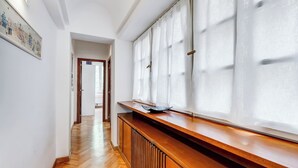 Ein Flur mit Holzboden, Heizkörper und einem fenster mit Vorhängen.
