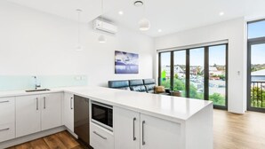 A modern kitchen with white cabinetry, a built-in oven, and a large island.