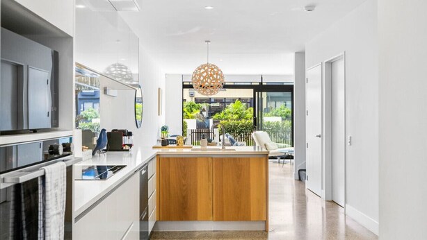 A modern kitchen with a wooden island, built-in appliances, and a view of the outdoors. - Hobsonville Point Enchanter with Parking and Wi-fi (Auckland West)