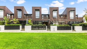A modern residential building with a symmetrical facade, large windows, and a well-maintained lawn. - Hobsonville Point Enchanter with Parking and Wi-fi (Auckland West)