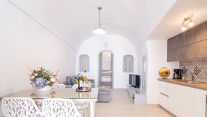 Une cuisine moderne avec des meubles blancs, un plan de travail en bois et un coin repas comprenant une table en verre et des chaises blanches.