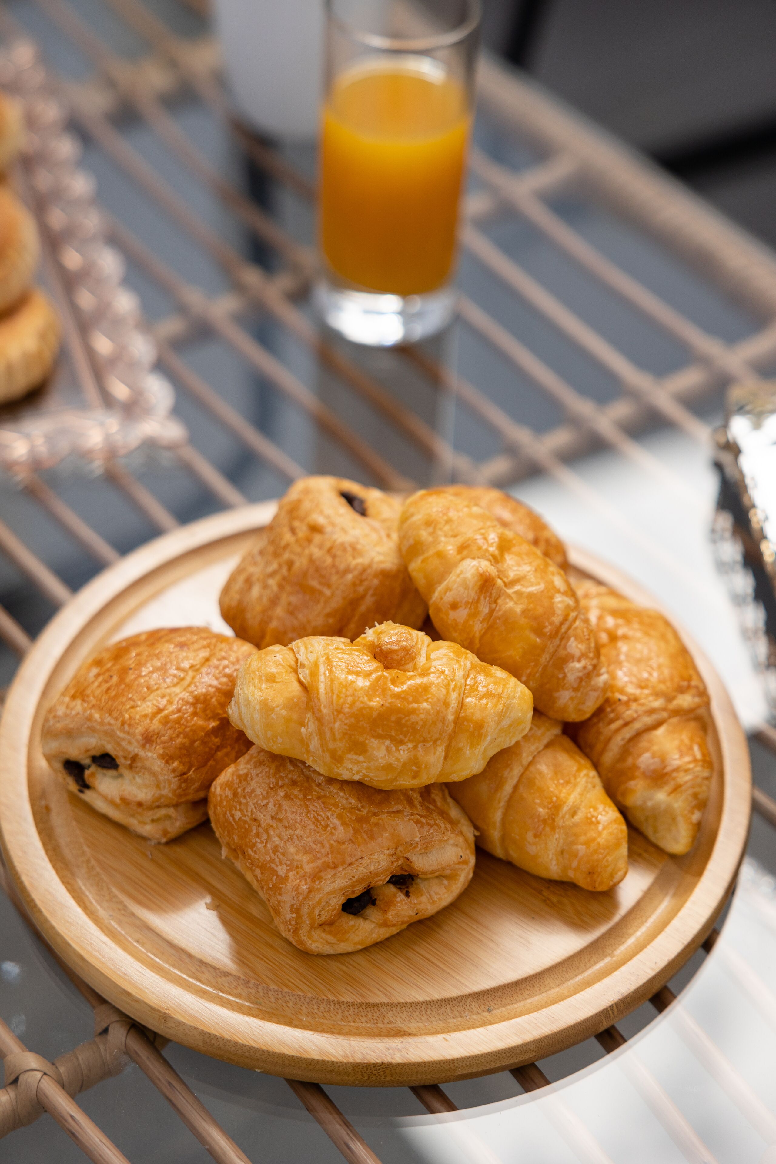 A wooden tray with croissants on a wire table.