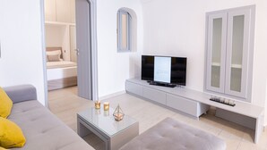 Un salon moderne comprenant un canapé, une table basse, un téléviseur et un petit coin repas.