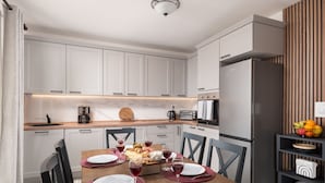 Une cuisine moderne avec des armoires blanches, un comptoir en bois et un four encastré. On y trouve une table à manger mise avec des assiettes, des verres et des couverts.
