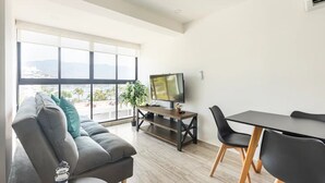 A modern living room with a sofa, TV, dining table, and chairs. - Departamento Astoria (Acapulco de Juarez)