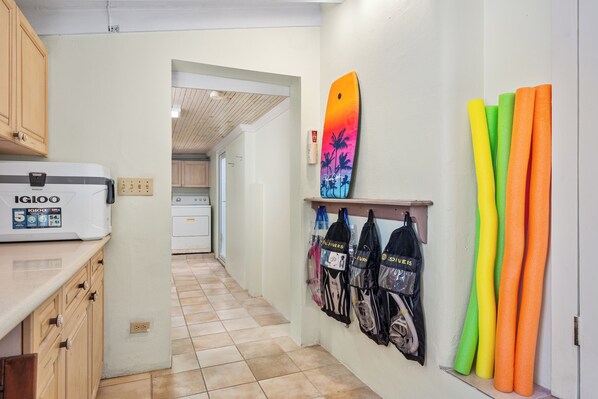 A kitchen with wooden cabinets, a microwave, and a surfboard on the wall. - 50 shades of blue (Nassau)