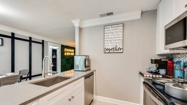 A modern kitchen with a large island, built-in appliances, and a decorative sign on the wall.