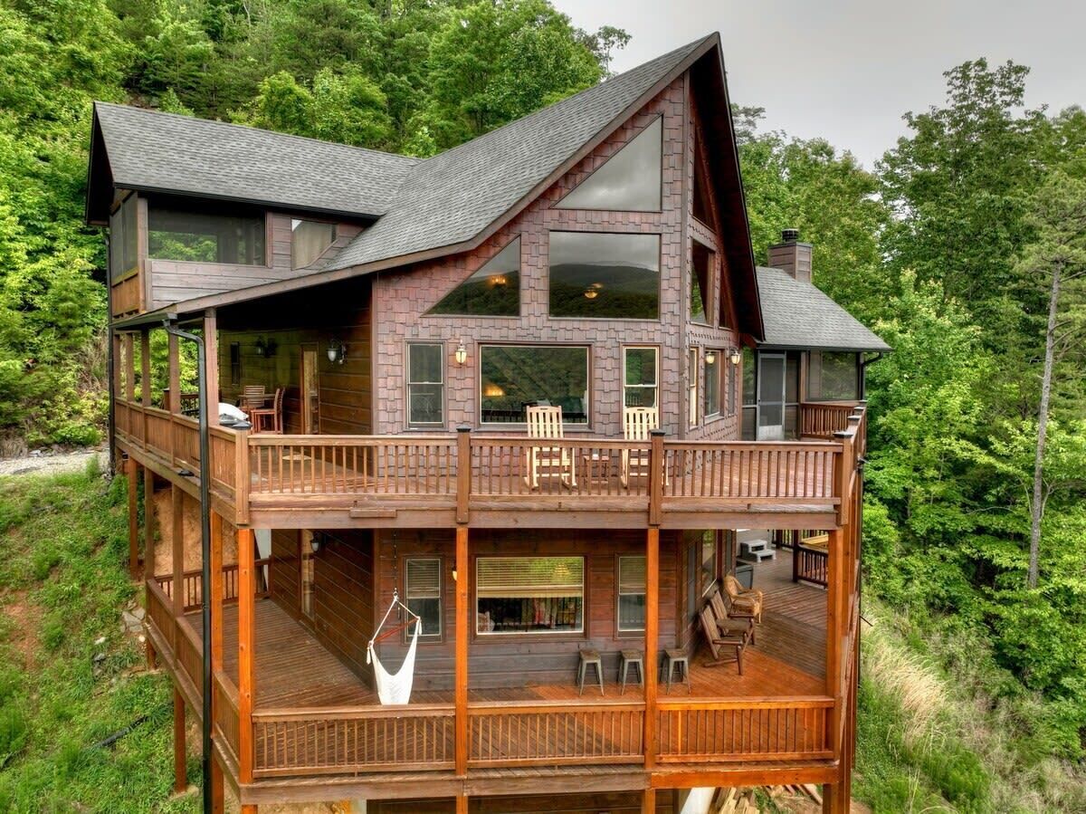 A multi-level wooden cabin with a balcony, large windows, and a deck area.