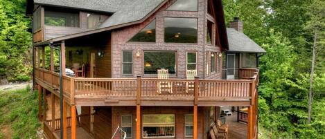 A multi-level wooden cabin with a balcony, large windows, and a deck area.