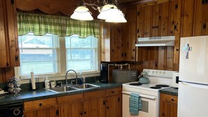 A kitchen with wooden cabinets, a stove, a sink, and a refrigerator. - Peaceful Farm Getaway (Mullins)