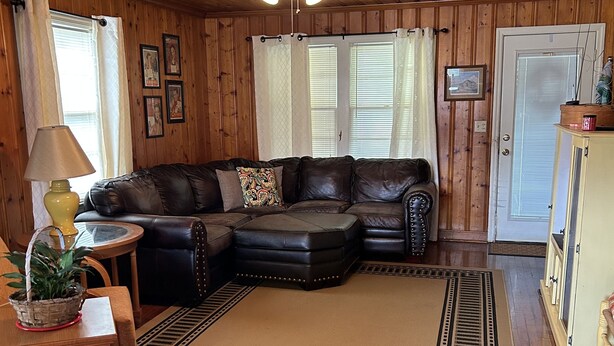 A cozy living room with a sectional sofa, wooden floors, a ceiling fan, and a door with a window. - Peaceful Farm Getaway (Mullins)