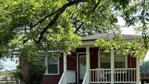 A small, single-story house with a white porch and steps leading to a front door. - Peaceful Farm Getaway (Mullins)