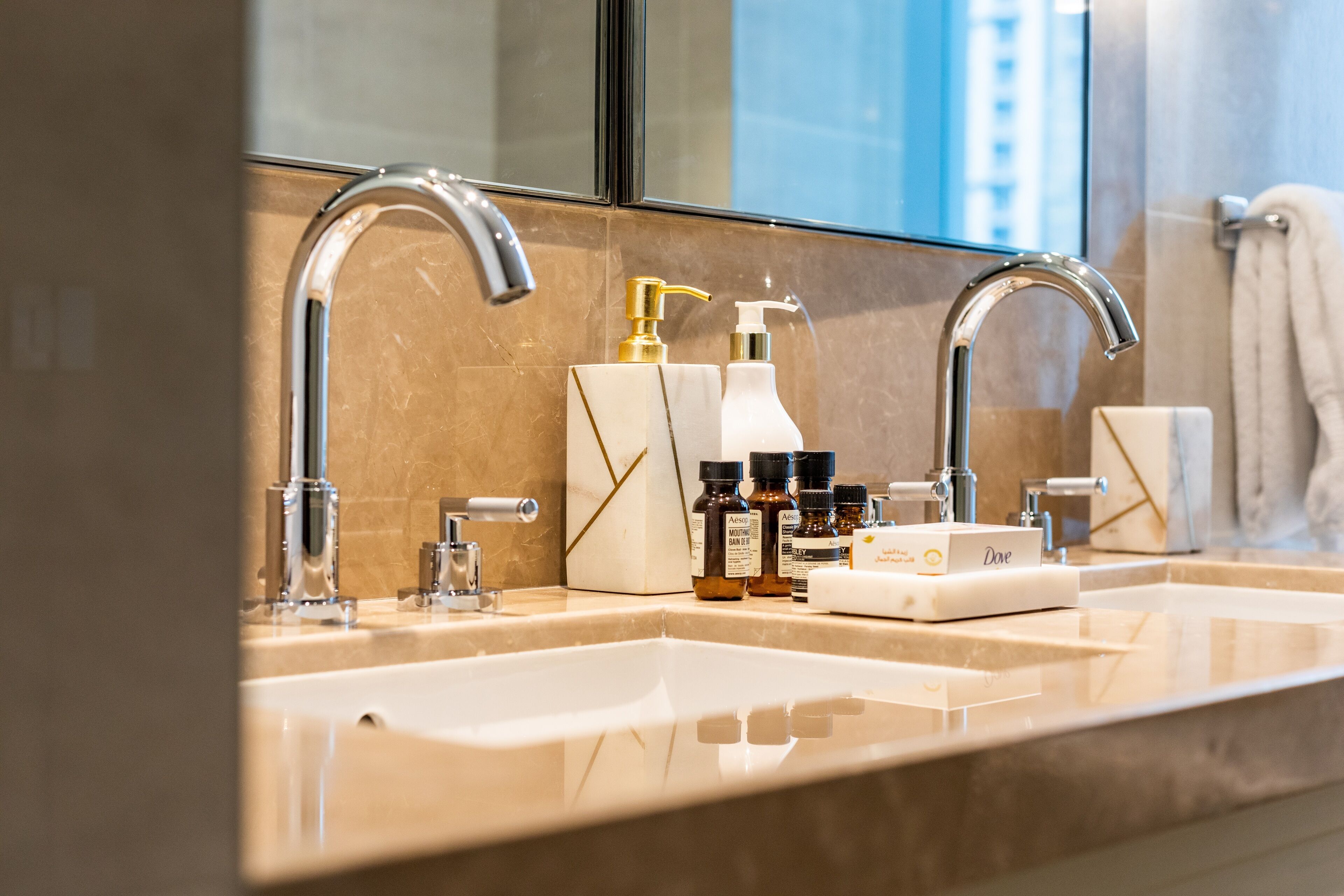 A modern bathroom with dual sinks, a large mirror, and various toiletries.